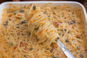 Creamy baked Boursin pasta with spaghetti, spinach, tomatoes, and blended zucchini sauce in a white baking dish