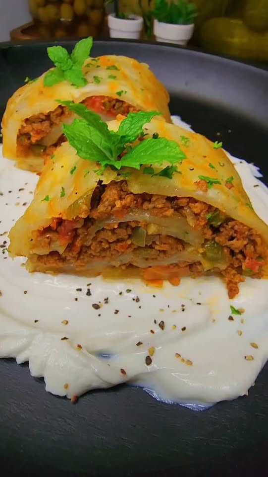 Sliced potato roll filled with spiced ground beef, tomato and green bell pepper, served over a smooth white sauce and topped with fresh mint and parsley
